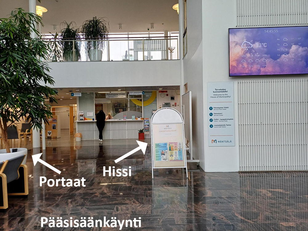 Kuvassa nuolin näytetty kunnantalon hissin ja portaiden sijainnit aulassa.