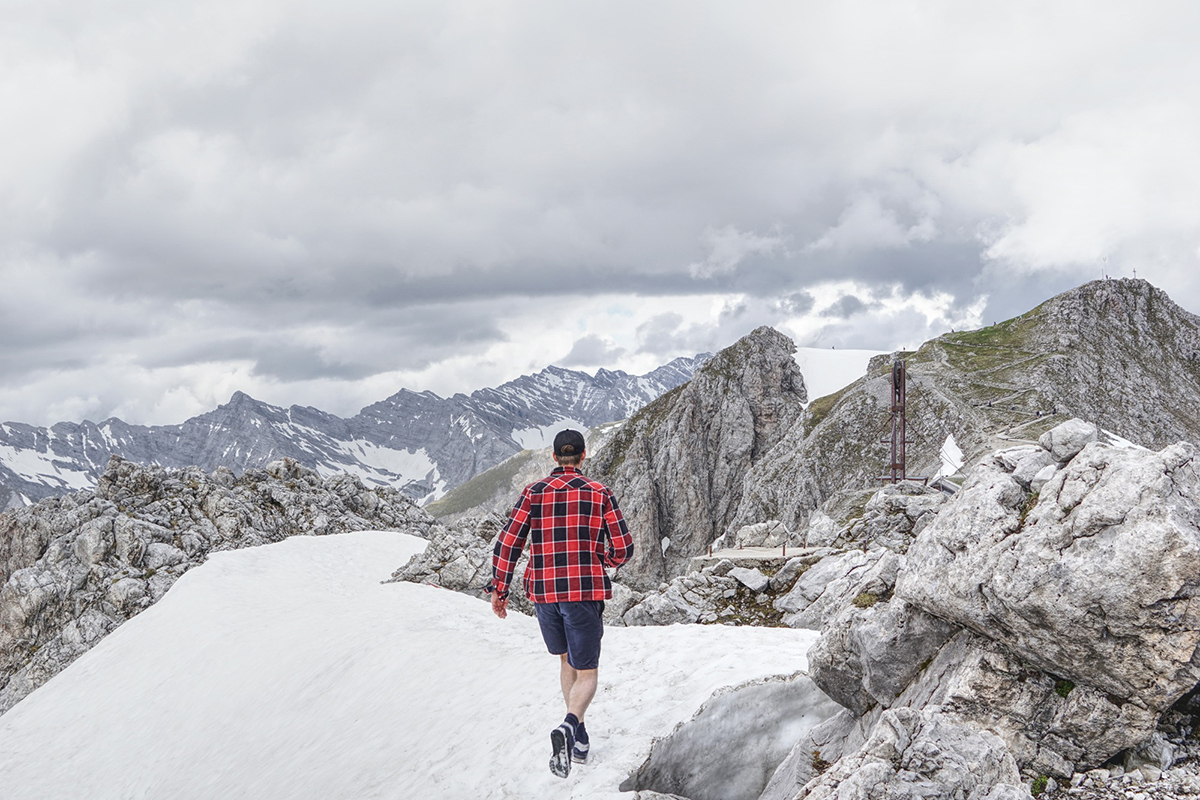 Man walking on the snow in shorts on top of an alpine mountain in tyrol