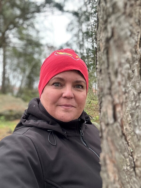 Kuvassa lähikuva opettajasta metsässä. Hänellä on päässään pipo.