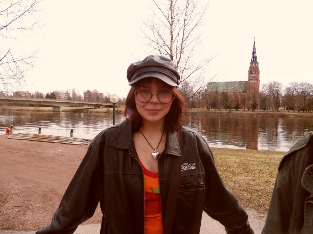 Kuvassa lakkipäinen ja silmälasipäinen nuori Porin Pohjoisrannassa. Joen takana näkyy Keski-Porin kirkko.